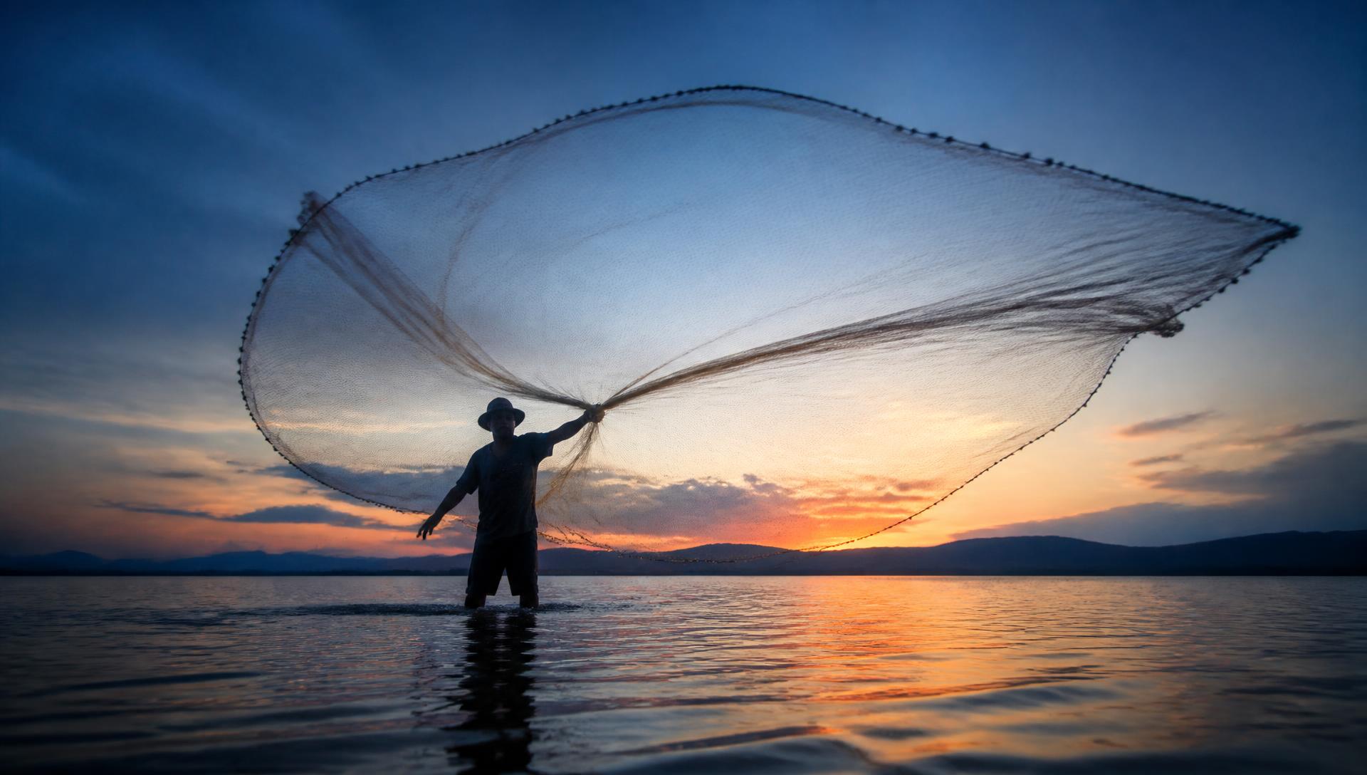 A fisherman casting a net at sunset, the sun low over calm water